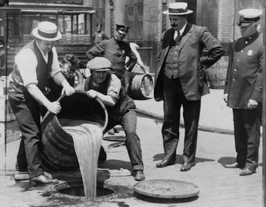Men pouring alcohol out of a barrel during a prohibition raid.